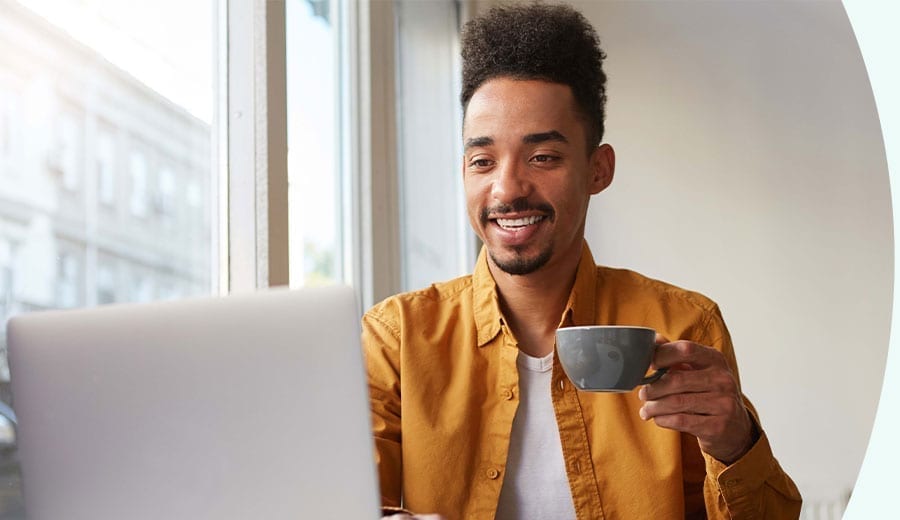 En man som dricker kaffe framför en dator